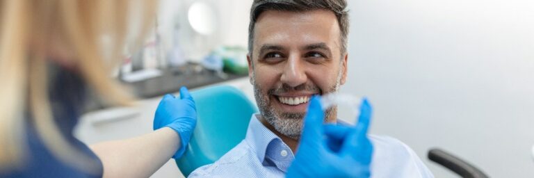 Eine junge Zahnärztin zeigt einem Patienten in einer Zahnklinik eine Invisalign Klammer, eine Zahnuntersuchung und das Konzept Gesunde Zähne