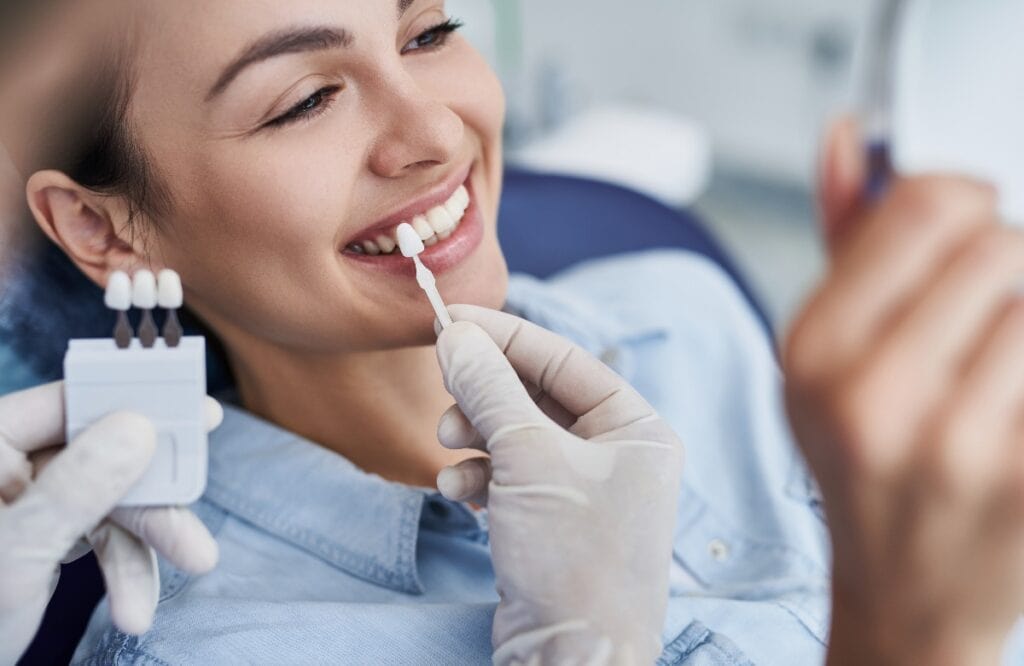 Male dentist choosing color for woman teeth