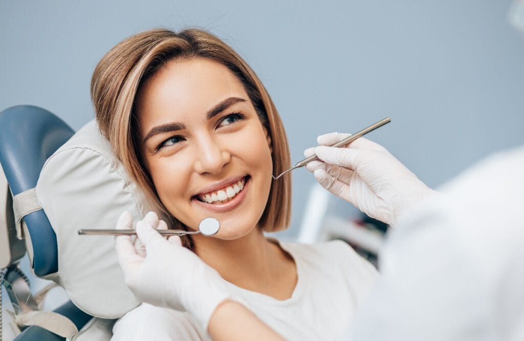 portrait of young blond good-looking woman on dental examination, treating teeth in professional orthodontic clinic, look at doctor and smile